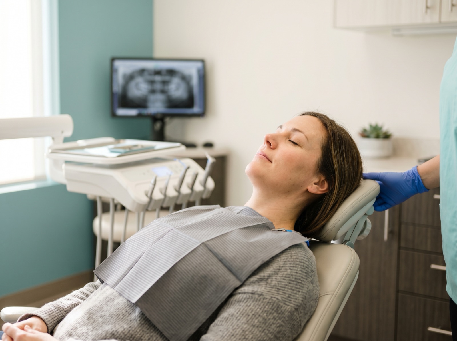 A deeply relaxed adult patient reclining calmly with eyes closed in a modern dental chair